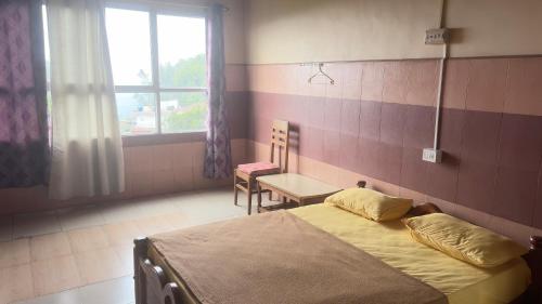 a bedroom with a bed and a table and a window at Vega tourist lodge in Madikeri