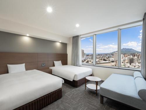 a hotel room with two beds and a window at Hotel Oriental Express Kagoshima Tenmonkan in Kagoshima