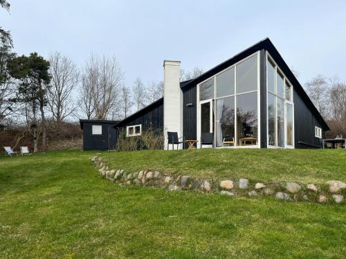 a black house with glass windows on a green field at Architect's House With Panoramic View In Lumsås in Lumsås