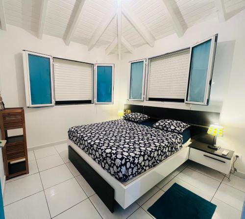 ein Schlafzimmer mit einem Bett in einem Zimmer mit Fenstern in der Unterkunft Paradis des sables B in La Désirade