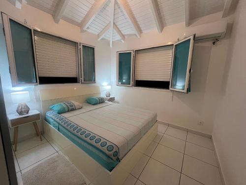 ein Schlafzimmer mit einem Bett in einem Zimmer mit Fenstern in der Unterkunft Paradis des sables B in La Désirade