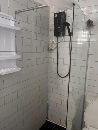 a shower in a white tiled bathroom with a toilet at Beachfront Hotel Cha Am in Cha Am
