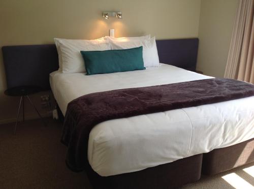 a large bed with a blue pillow on top of it at Sails on the Lake in Taupo