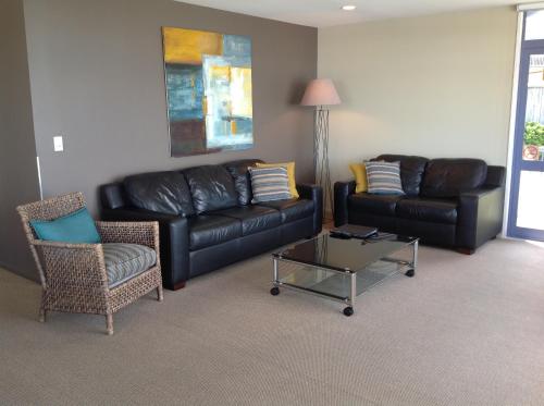 a living room with a leather couch and a coffee table at Sails on the Lake in Taupo
