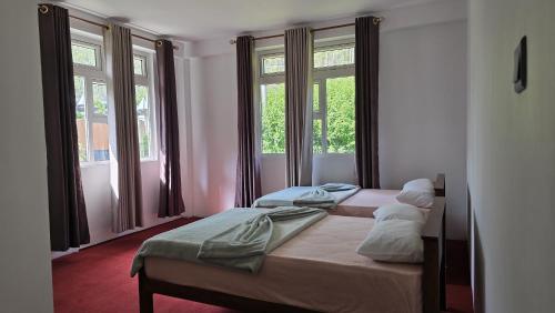two beds in a room with two windows at Mellow Breeze - Nuwara Eliya in Nuwara Eliya