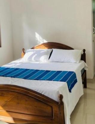 a bed with blue and white sheets and pillows at Meegoda Villa in Kalutara
