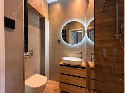 a bathroom with a sink and a toilet and a mirror at Apartament GreenHills 3 in Wałbrzych