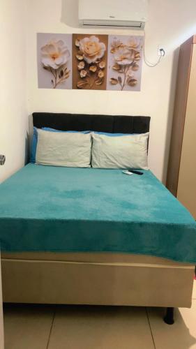 a bedroom with a bed with blue sheets and flowers on the wall at Cantinho da day in Aracaju