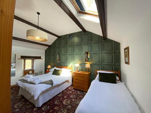 a bedroom with two beds and a green wall at Swaledale Watch Garden Annexe in Wigton