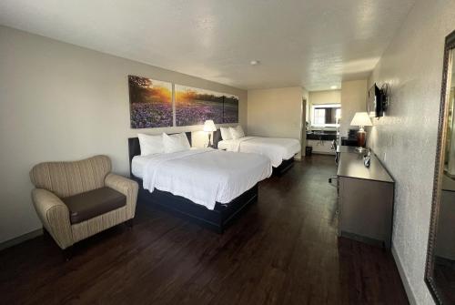 a hotel room with two beds and a chair at Days Inn & Suites by Wyndham - Canton First Monday Trade Days in Canton