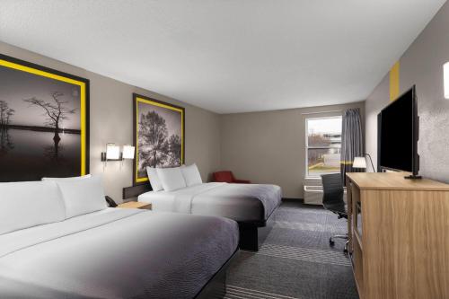 a hotel room with two beds and a flat screen tv at Super 8 by Wyndham Chattanooga East - Hamilton Place in Chattanooga