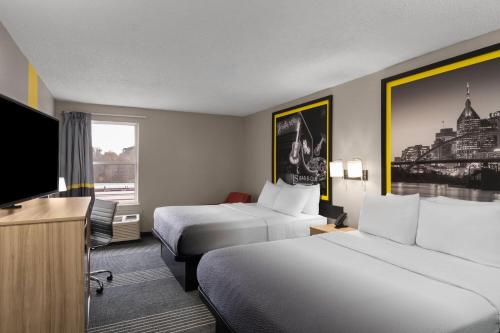 a hotel room with two beds and a flat screen tv at Super 8 by Wyndham Chattanooga East - Hamilton Place in Chattanooga