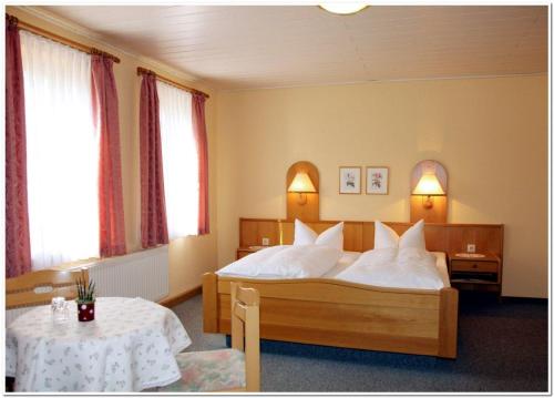 a bedroom with a bed with white pillows and a table at Pension Teichschänke in Zwönitz