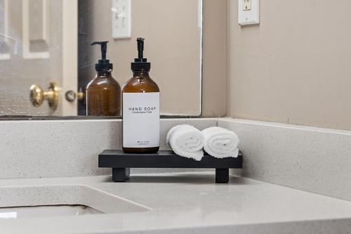 a bathroom sink with a bottle of alcohol and towels at 5BR Wild Rose- Meadows, AC, Garage, Sleeps 12 in Edmonton