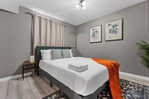 a bedroom with a bed with white sheets and an orange blanket at 5BR Wild Rose- Meadows, AC, Garage, Sleeps 12 in Edmonton