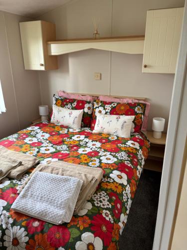 a bedroom with a bed with a colorful flower blanket at Browns caravan rentals, 8 berth, the chase, ingoldmells in Skegness