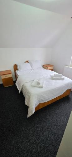 a bedroom with a large bed with white sheets at Pensiune Urban in Borsec