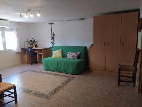 a living room with a green couch and a desk at La caseta del llorer in Catadau