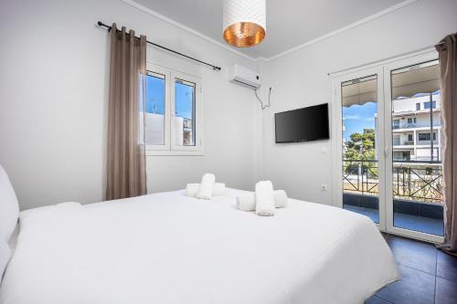 a white bedroom with a bed and a tv at Athenean Sea Breeze in Vari