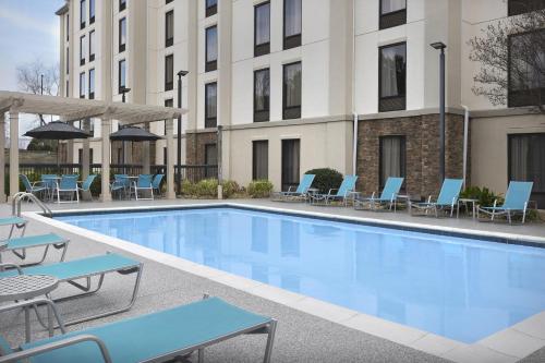 a swimming pool with chairs and a building at Hampton Inn & Suites Greenville/Spartanburg I-85 in Duncan