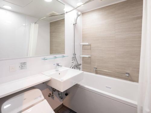 a white bathroom with a sink and a mirror at Comfort Hotel Takamatsu in Takamatsu