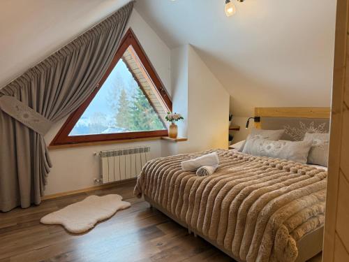 a bedroom with a large bed with a large window at Domek Zyngierka Tatra View - balia I sauna na wyłączność in Bańska Wyżna