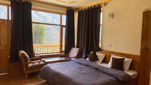 a bedroom with a bed and a large window at Hotel sno cottage in Vashisht