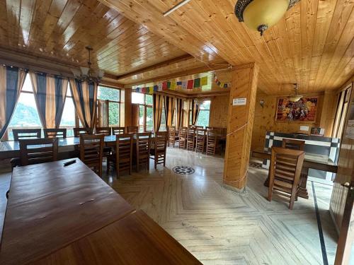a dining room with wooden tables and chairs at Hotel sno cottage in Vashisht