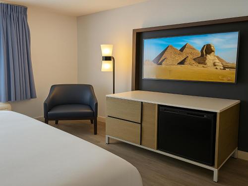 a hotel room with a tv and a chair at Rancho San Diego Inn & Suites in El Cajon