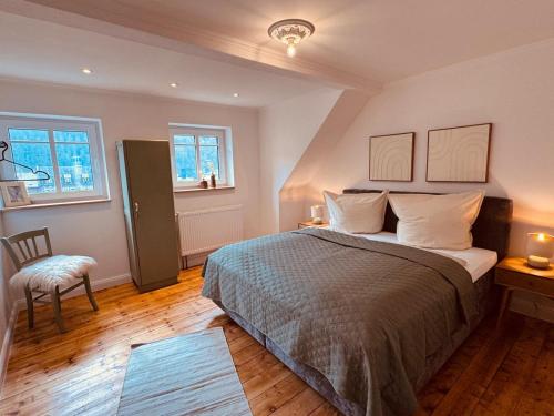 a bedroom with a bed and a chair and two windows at Residenz Moselliebe Traben in Traben-Trarbach