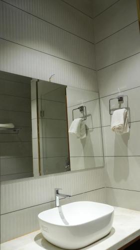 a bathroom with a white sink and a mirror at Royal palm hotel and resort in Niāl