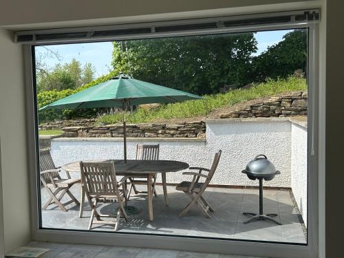 a patio with a table and chairs and an umbrella at Sharpley Hall Garden Studio not far from Seaham Beach offering Quiet Private Stay with Secure Parking in Seaham