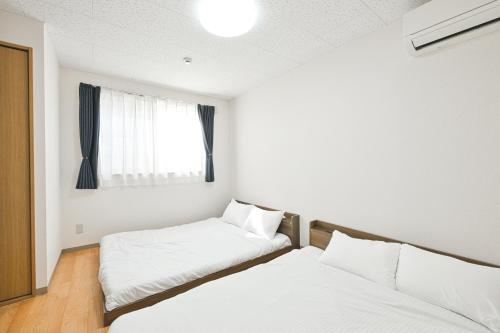 two beds in a small room with a window at STAY IN PASSION in Asahikawa