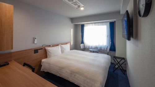 a hotel room with a bed and a window at Toyoko Inn Koriyama in Koriyama