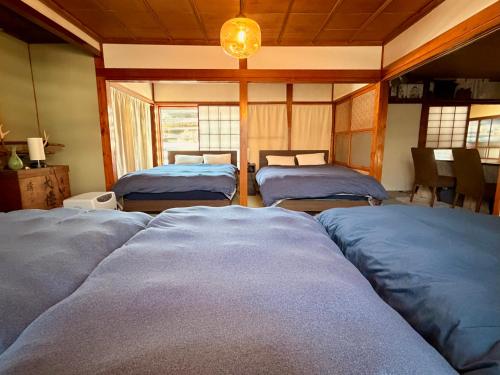 a room with three beds and a table and windows at HAYU Hearth Yuzawa in Yuzawa