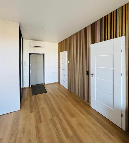an empty room with wooden floors and white doors at Apartamentai parke, su vaizdu į upę - Šešupės terasos in Marijampolė