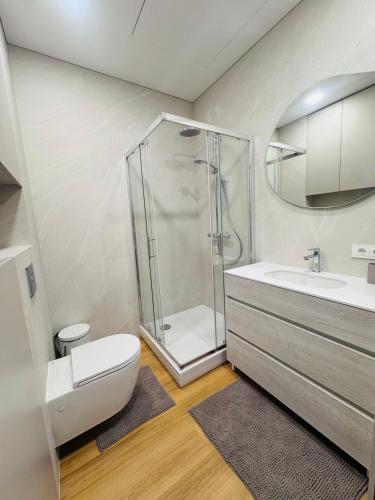 a bathroom with a shower and a toilet and a sink at Apartamentai parke, su vaizdu į upę - Šešupės terasos in Marijampolė