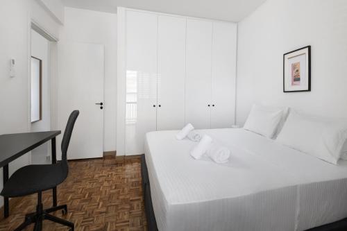 a white bedroom with a desk and a bed at Urban Condo Promitheos in Nicosia