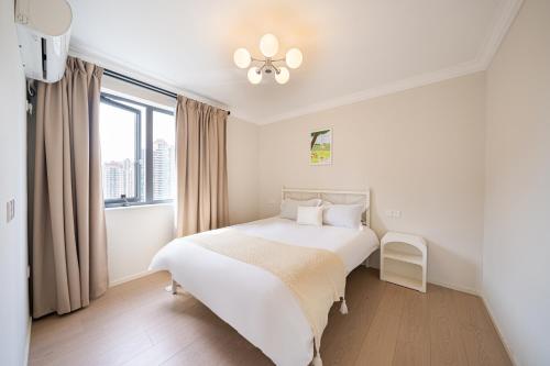a white bedroom with a bed and a window at Today-Lujiazui Riverside,Bund Riverview in Shanghai