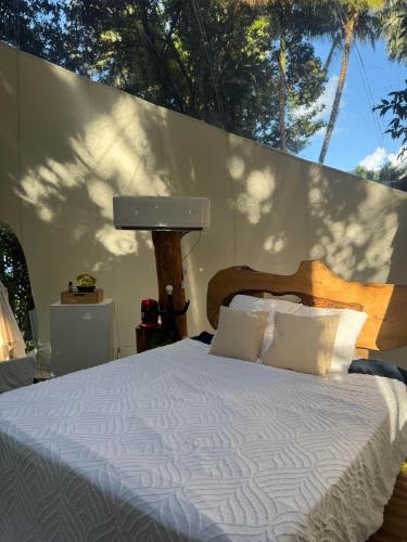 a bedroom with a bed with white sheets and trees at Bulle skys evasion in Gros-Morne