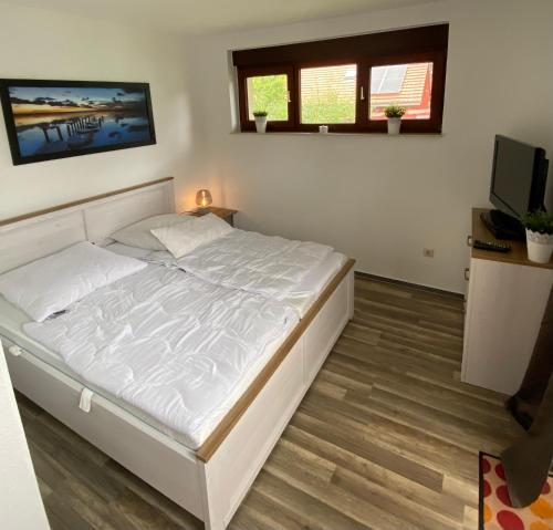 a bedroom with a white bed and a television at Ferienwohnung Plaue Auszeit mit Privatstrand und Bootsliegeplatz in Zislow