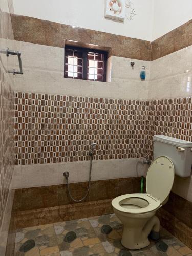 a bathroom with a toilet and a window at Villa Mud Apple in Varkala