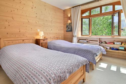 two beds in a bedroom with wooden walls at Garden Heart of the village Swedish Stove in Champéry