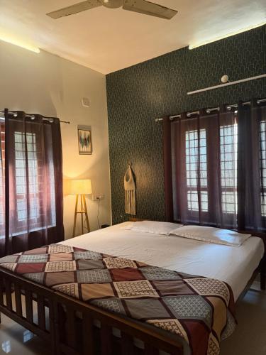 a bed in a bedroom with green walls and windows at Villa Mud Apple in Varkala