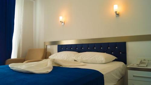 a bed with a blue blanket and white pillows at Taşucu Kaptan Suit Otel in Silifke