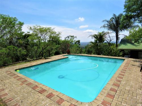 a large blue swimming pool with a brick patio at Viewpoint Lodge & Safari Tours in Hazyview