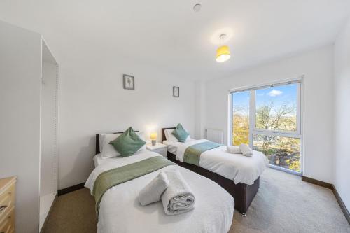 three beds in a room with a window at Stylish long & short stay flat with parking & Wifi sleeps 5 in Maidstone