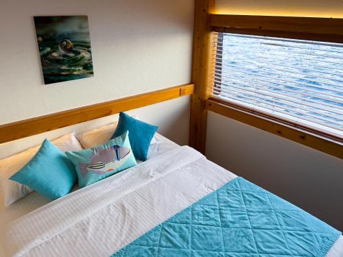 a bedroom with a bed with blue pillows and a window at RITRELLA FLOATING HOTEL&YACHT - FREE beach access daily - Full board meal plan in Male City