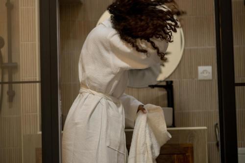 a woman in a white robe standing in front of a mirror at Le felix in Antananarivo