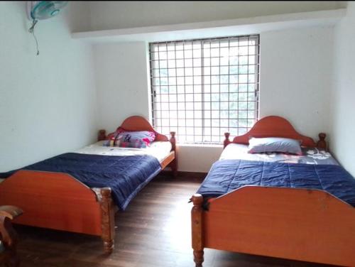 two beds sitting in a room with a window at COORG CLlMATE FARM HOUSE in Madikeri